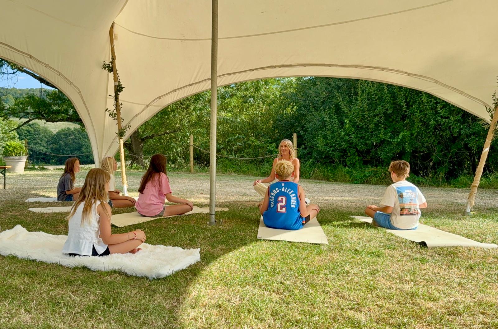 Children seated on yoga mats during a family yoga session outdoors